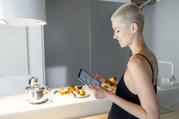 Mujer controla electrodomésticos de cocina inteligentes con dispositivo móvil — Foto de Stock