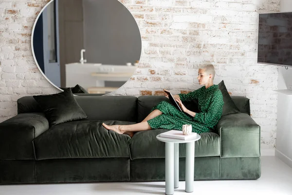 Donna elegante con tablet digitale sul divano di casa — Foto Stock