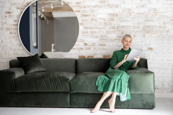 Mujer con estilo con tableta digital en el sofá en casa —  Fotos de Stock