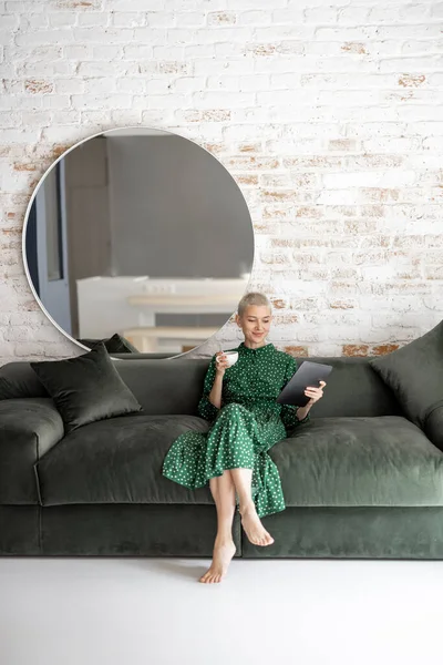 Tyylikäs nainen digitaalinen tabletti sohvalla kotona — kuvapankkivalokuva