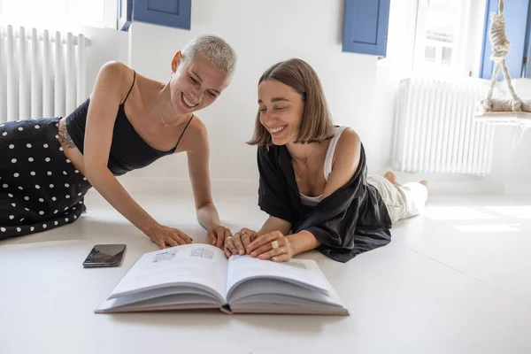 Lesbianas pareja leyendo libro en casa — Foto de Stock