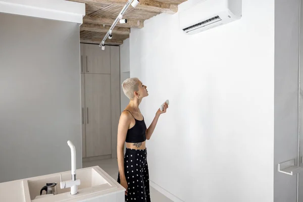 Kobieta ustawia temperaturę na klimatyzatorze w domu — Zdjęcie stockowe
