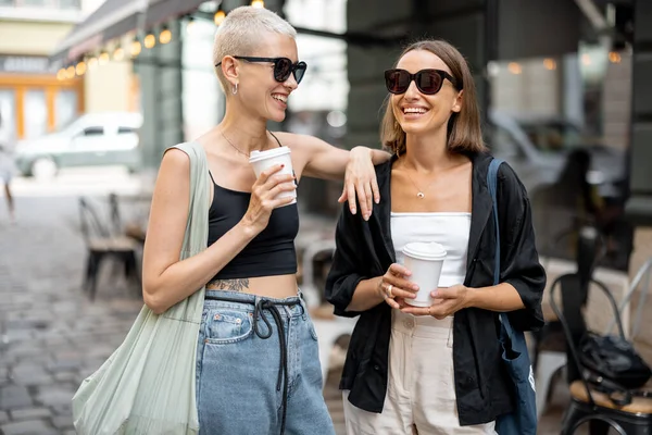 スタイリッシュな女性のカップルが屋外のコーヒーカップと一緒に立って — ストック写真