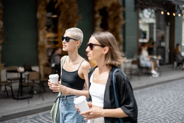 Elegante pareja femenina de pie junto con un café tazas al aire libre —  Fotos de Stock