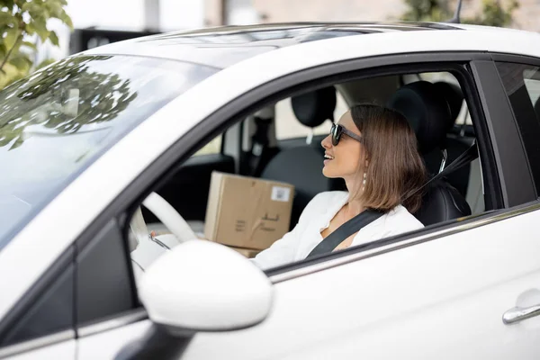 Donna che guida auto con pacchi su un sedile del passeggero — Foto Stock