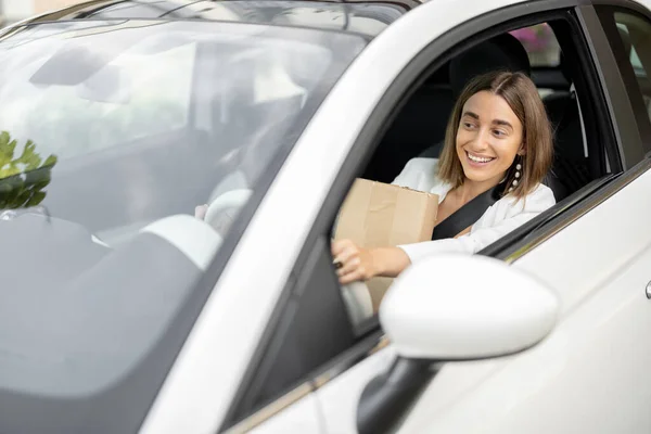 Frau fährt Auto mit Paketen in der Hand — Stockfoto