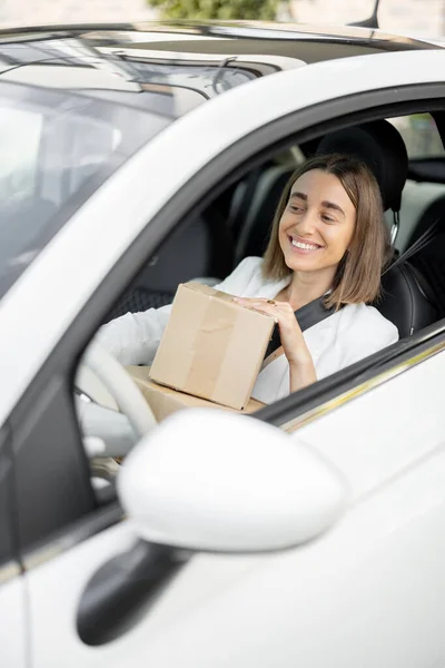 Žena řídí auto s balíčky v rukou — Stock fotografie