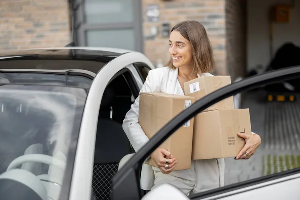 Frau mit Paketen in der Nähe ihres Autos und Hauses — Stockfoto