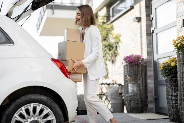 Frau mit Paket in der Nähe ihres Autos und ihres Hauses — Stockfoto