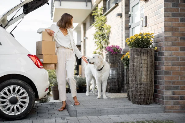 Žena s balíčky poblíž svého auta a domů — Stock fotografie