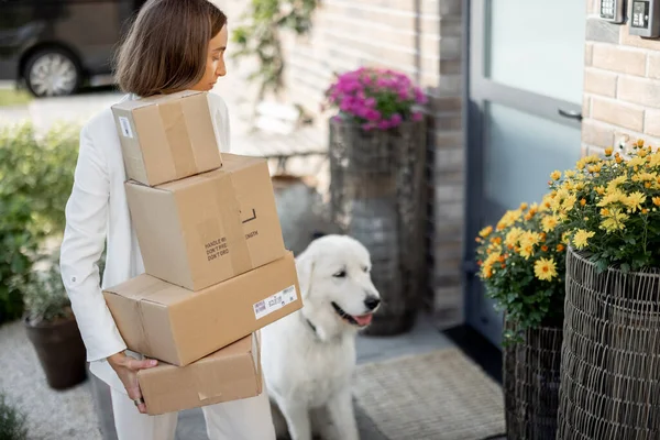 Frau mit Paket und Hund auf der Veranda ihres Hauses — Stockfoto