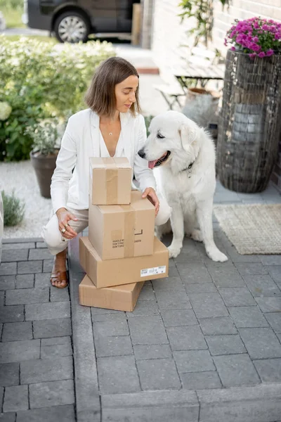 Frau mit Paket und Hund auf der Veranda ihres Hauses — Stockfoto