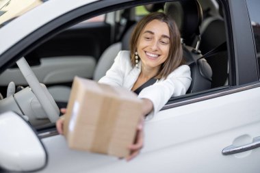 Hareket halindeyken araç camından paket alan kadın.