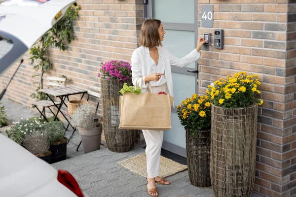 Mujer llegando a casa con comestibles y entra en un código para acceder a la puerta — Foto de Stock