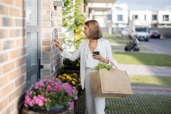 Mujer llegando a casa con comestibles y entra en un código para acceder a la puerta — Foto de Stock