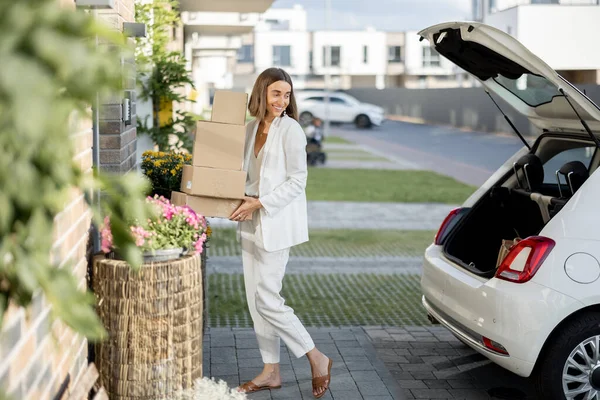 Donna con un pacchi vicino alla sua auto e casa — Foto Stock