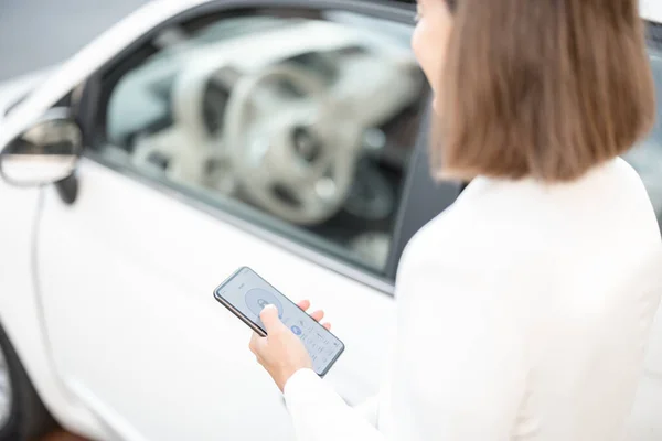 Γυναίκα ελέγχου αυτοκίνητο συναγερμού με κινητό τηλέφωνο — Φωτογραφία Αρχείου