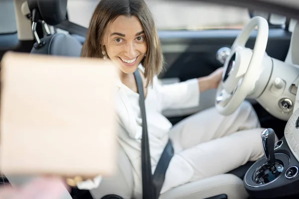 Frau erhält unterwegs ein Paket durch die Fahrzeugscheibe — Stockfoto