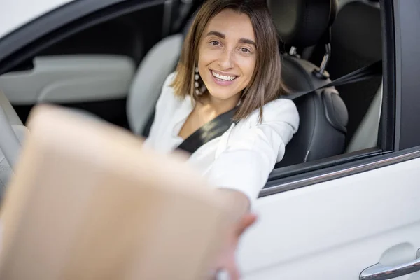 Frau erhält unterwegs ein Paket durch die Fahrzeugscheibe — Stockfoto