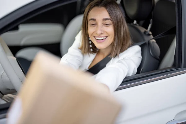 Frau erhält unterwegs ein Paket durch die Fahrzeugscheibe — Stockfoto