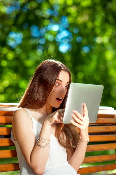 Jonge vrouw met digitale tablet in het park — Stockfoto