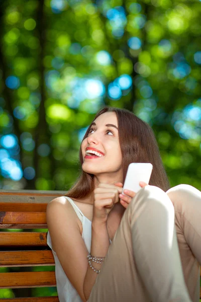 Parkta cep telefonu olan genç bir kadın. — Stok fotoğraf