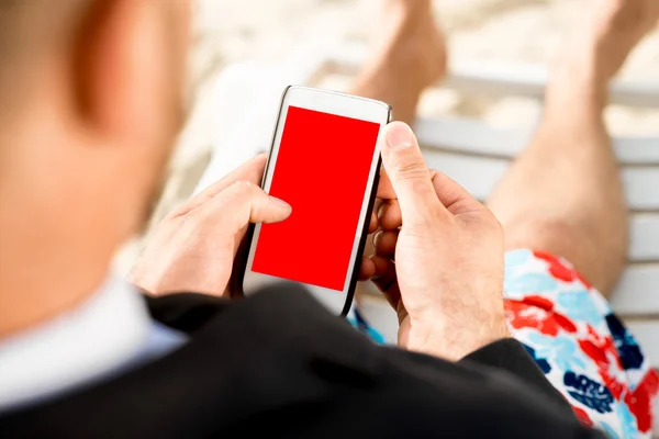 Uomo d'affari che tiene il cellulare sulla spiaggia — Foto Stock