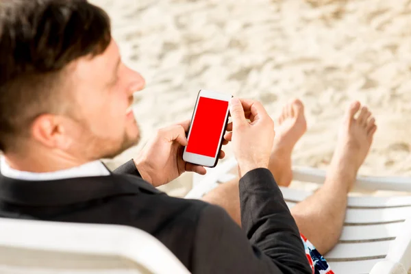 Businessman holding cellphone on the beach — Stock Photo, Image