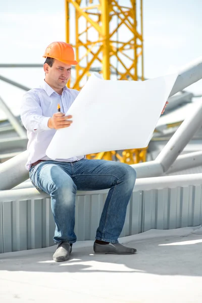 A foreman with drawings supervising the project at the construction. — Stock Photo, Image
