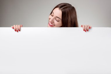 Studio gri arka plan üzerinde beyaz billboard gösterilen kadın