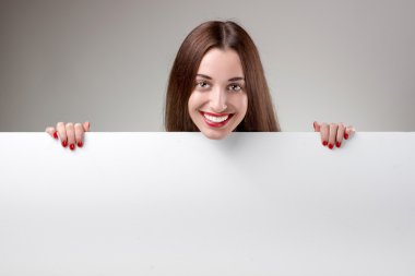Studio gri arka plan üzerinde beyaz billboard gösterilen kadın