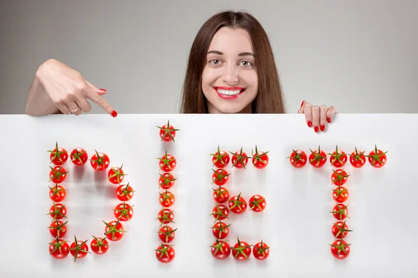 Frau zeigt auf weiße Plakatwand vor grauem Hintergrund im Studio — Stockfoto