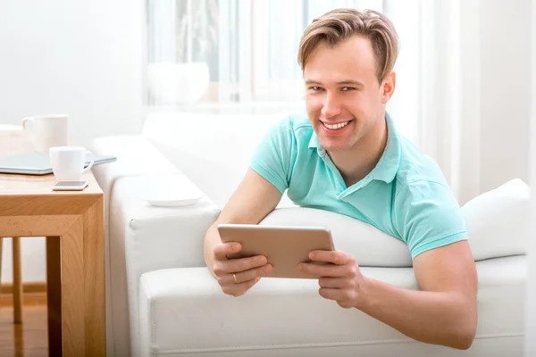 Muž s miniaplikace sedí doma — Stock fotografie
