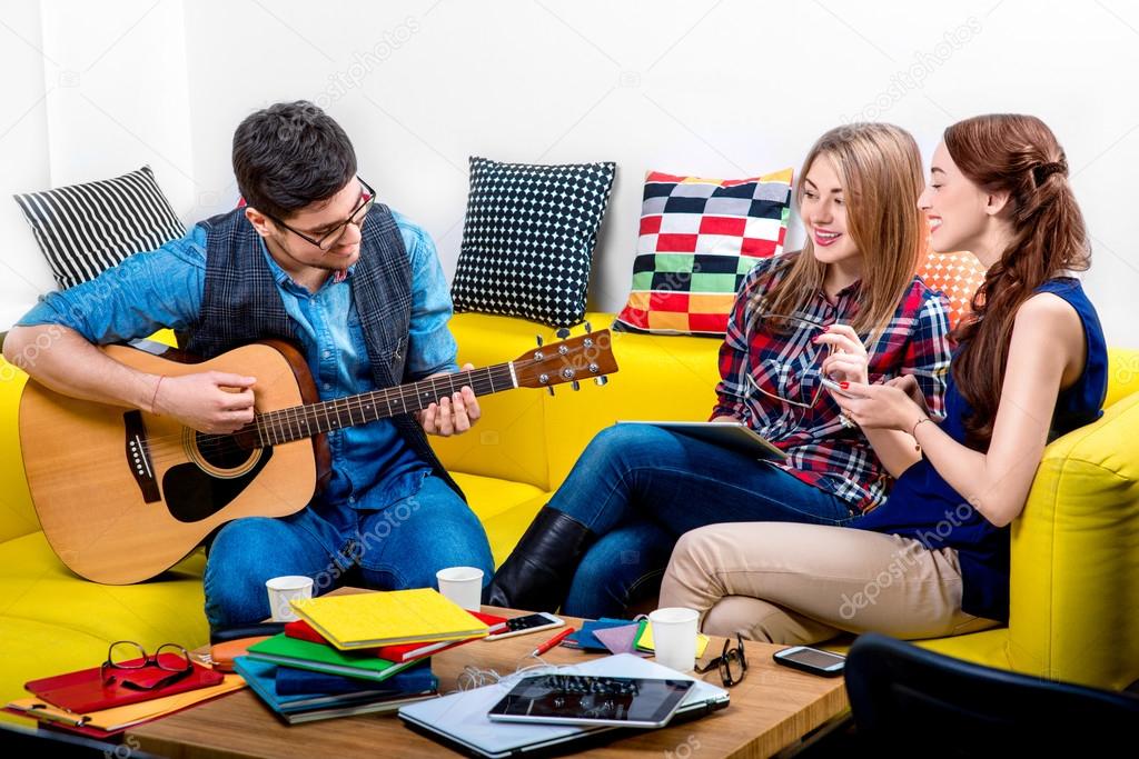 Man playing a guitar with girlfriends
