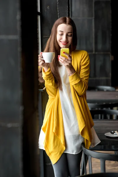 Femme avec téléphone et une tasse de café — Photo