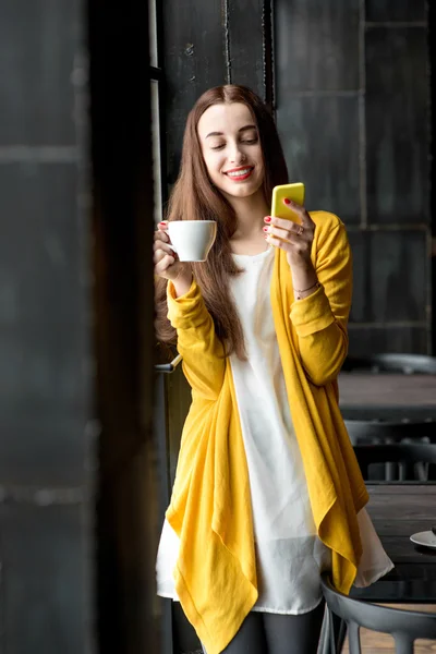 Mujer con teléfono y una taza de café — Foto de Stock