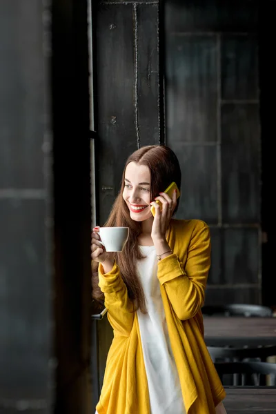 Mulher com telefone e uma xícara de café — Fotografia de Stock