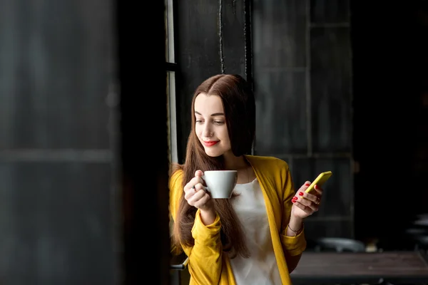 Женщина с телефоном и чашкой кофе — стоковое фото