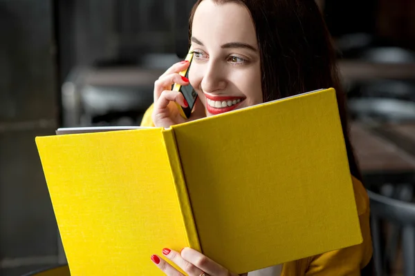 Vrouw met boek en mobiele telefoon — Stockfoto