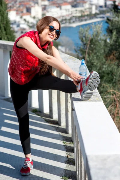 Sporty woman on the park alley with city view — Stock Photo, Image