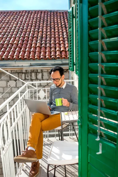 Man met laptop op het balkon — Stockfoto