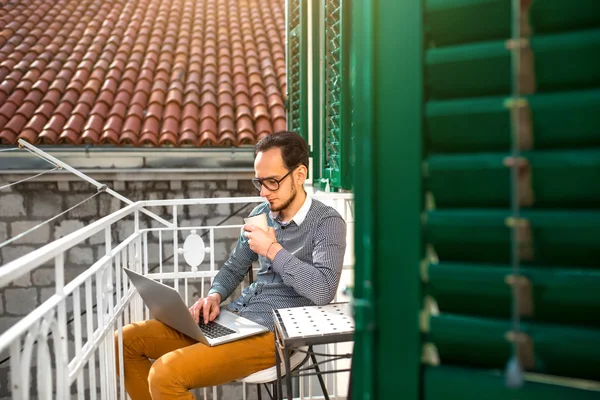 Man met laptop op het balkon — Stockfoto