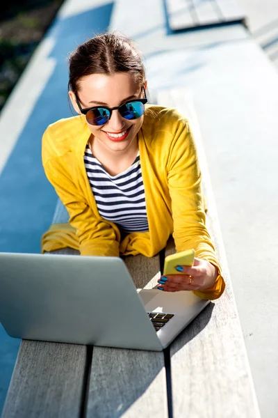 Femme avec ordinateur portable et téléphone à l'extérieur — Photo