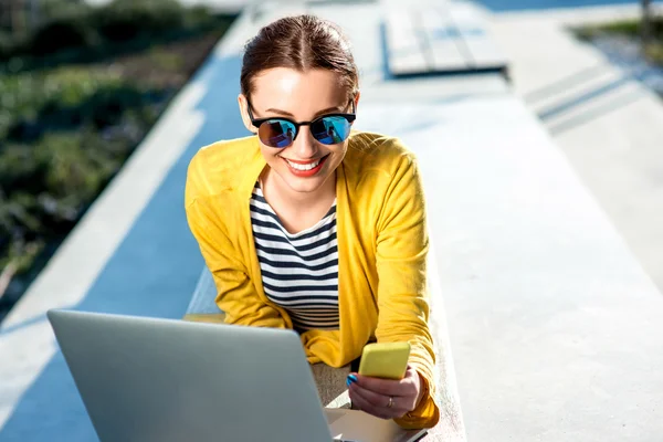 Woman with laptop and phone outdoors — Stock Photo, Image