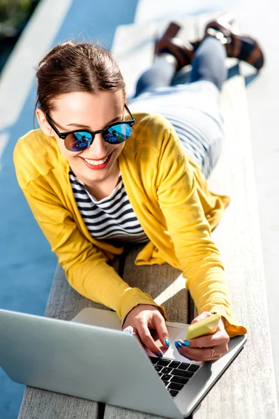 Vrouw met laptop en telefoon outdoors — Stockfoto