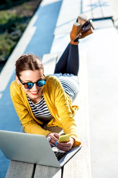 Femme avec ordinateur portable et téléphone à l'extérieur — Photo