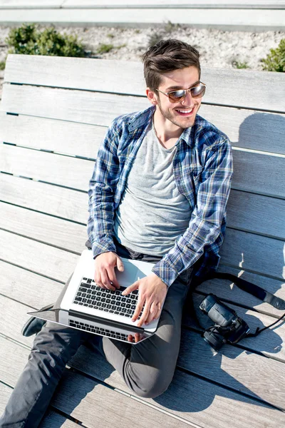 Young photographer with laptop and photo camera — Stock Photo, Image