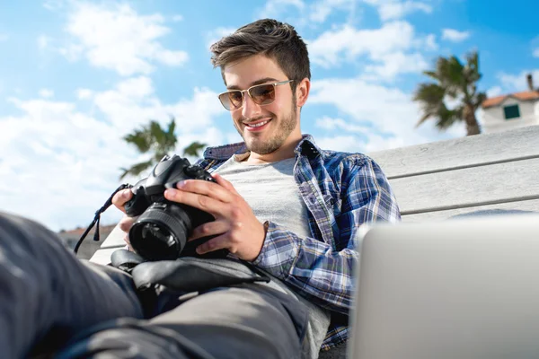 Jonge fotograaf met laptop en foto camera — Stockfoto