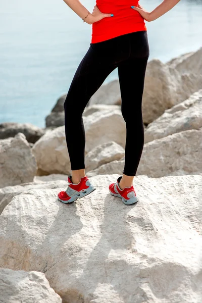 Sportos nő lába a sziklás tengerparton — Stock Fotó