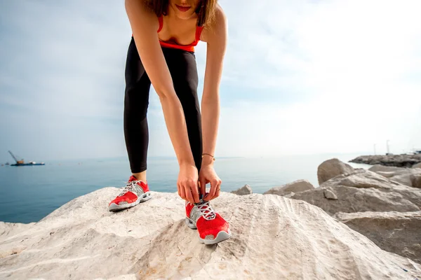 Sportieve vrouw benen op de rotsachtige strand — Stockfoto